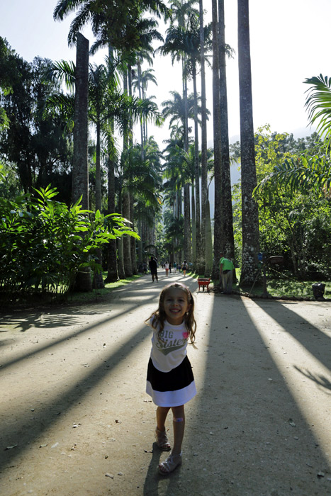 Julia fazendo pose com as palmeiras imperiais ao fundo
