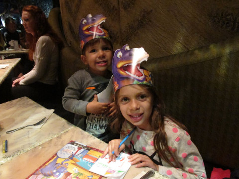 Julia e Eric com os chapéus de dinossauros que eles dão pras crianças na entrada